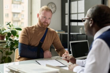 a man with injured arm talking having conversation with his personal injury attorney