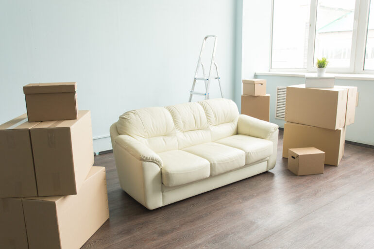 white sofa sits in a living room surrounded by packing boxes